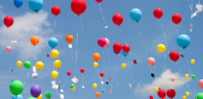 balloons with notes attached flying into the sky