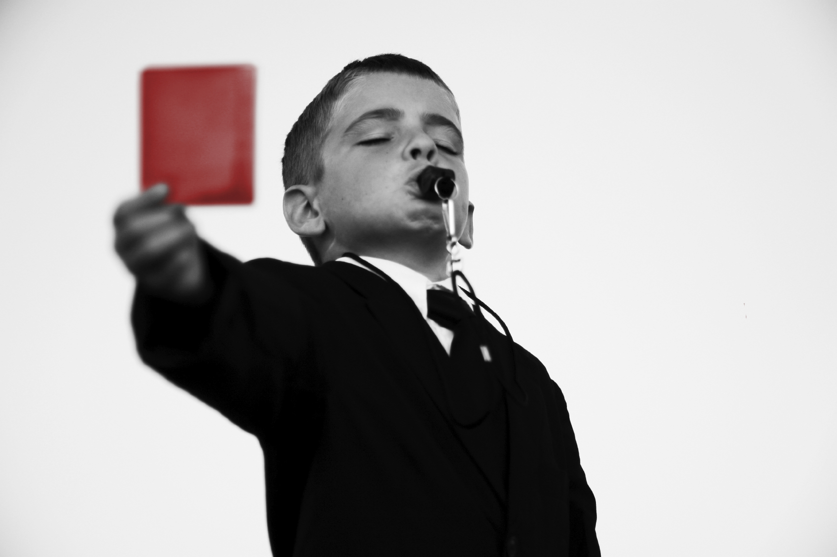 boy wearing a suit with a whistle showing a red card