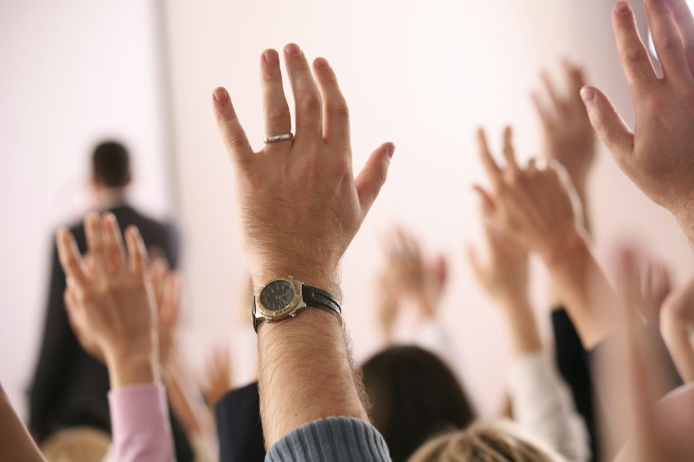 raised hands asking questions during a presentation