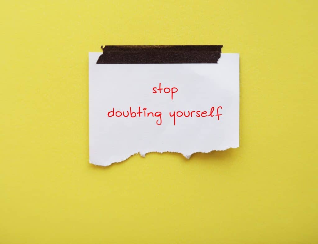 Note on yellow background with handwritten text saying stop doubting yourself