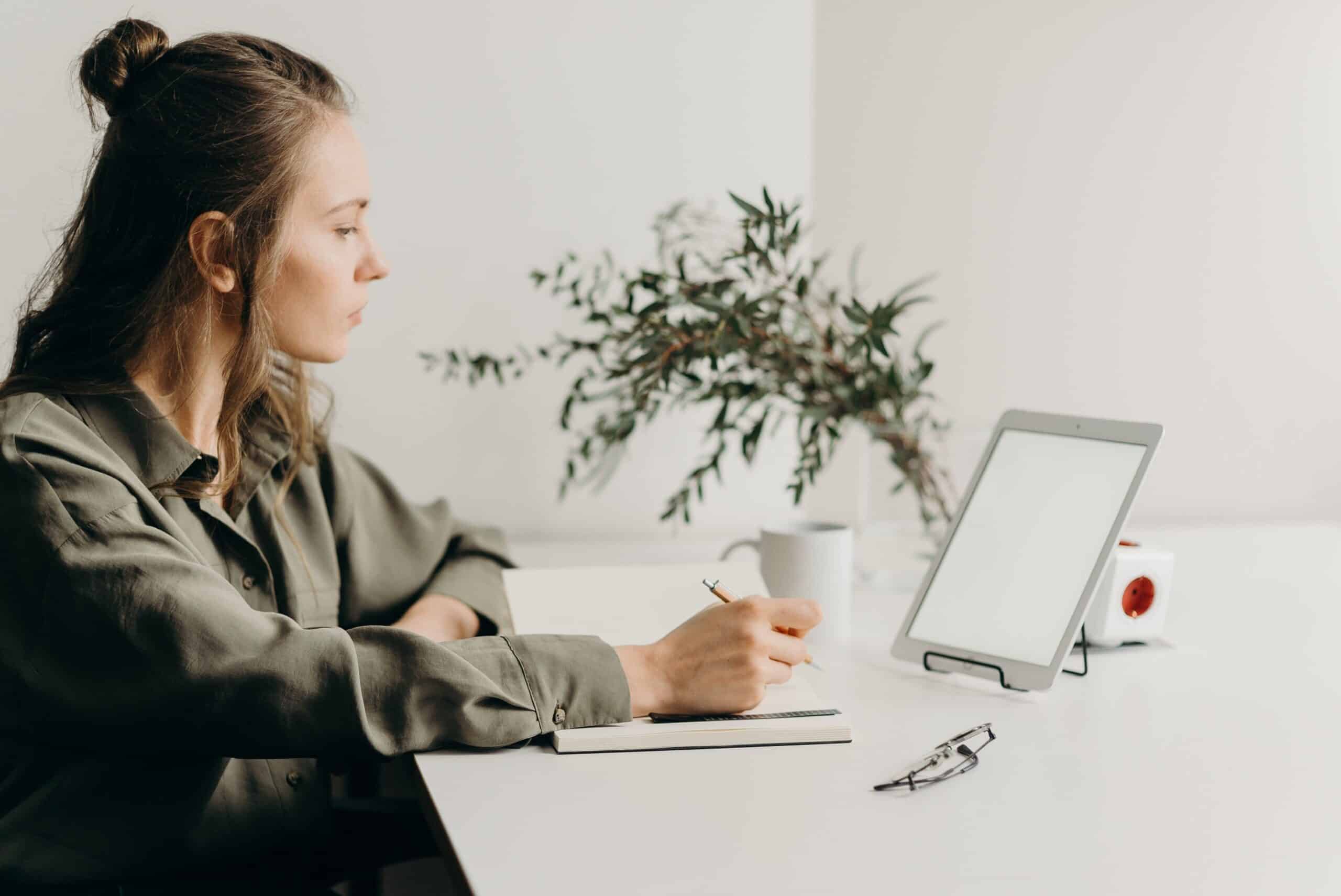 Young woman taking notes on webinar