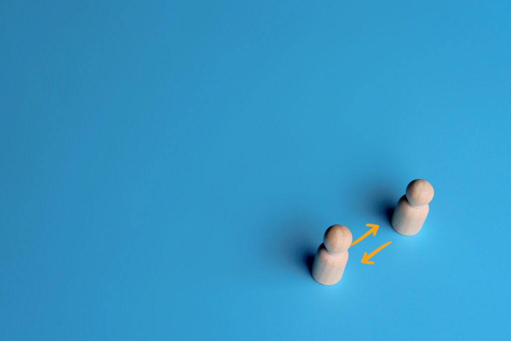 Wooden,Dolls,And,Exchange,Arrow,On,Blue,Background.,Copy,Space.